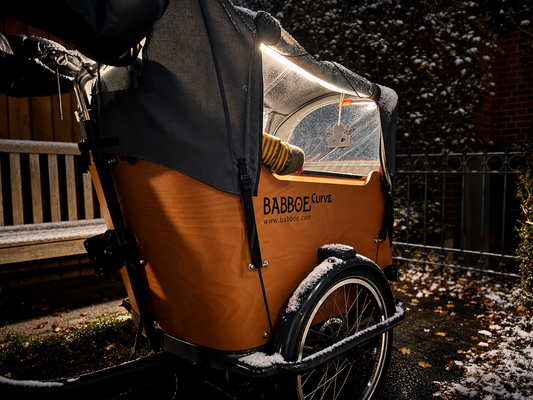Babboe Curve mit durch CargoGLOW beleuchtetem Regenverdeck bei Dunkelheit