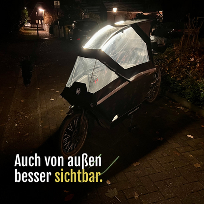 [de] Lastenrad mit von CargoGLOW beleuchtetem Regenverdeck, bei Dunkelheit von außen aufgenommen. Auch von außen besser sichtbar.