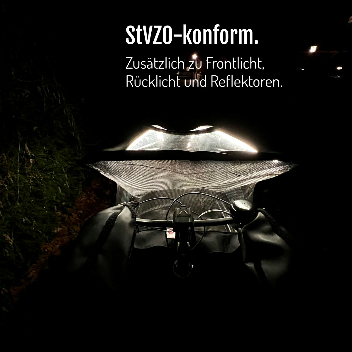 [de] Blick über den Lenker auf das von CargoGLOW beleuchtete Regenverdeck bei Dunkelheit. StVZO-konform, zusätzlich zu Frontlicht, Rücklicht und Reflektoren.