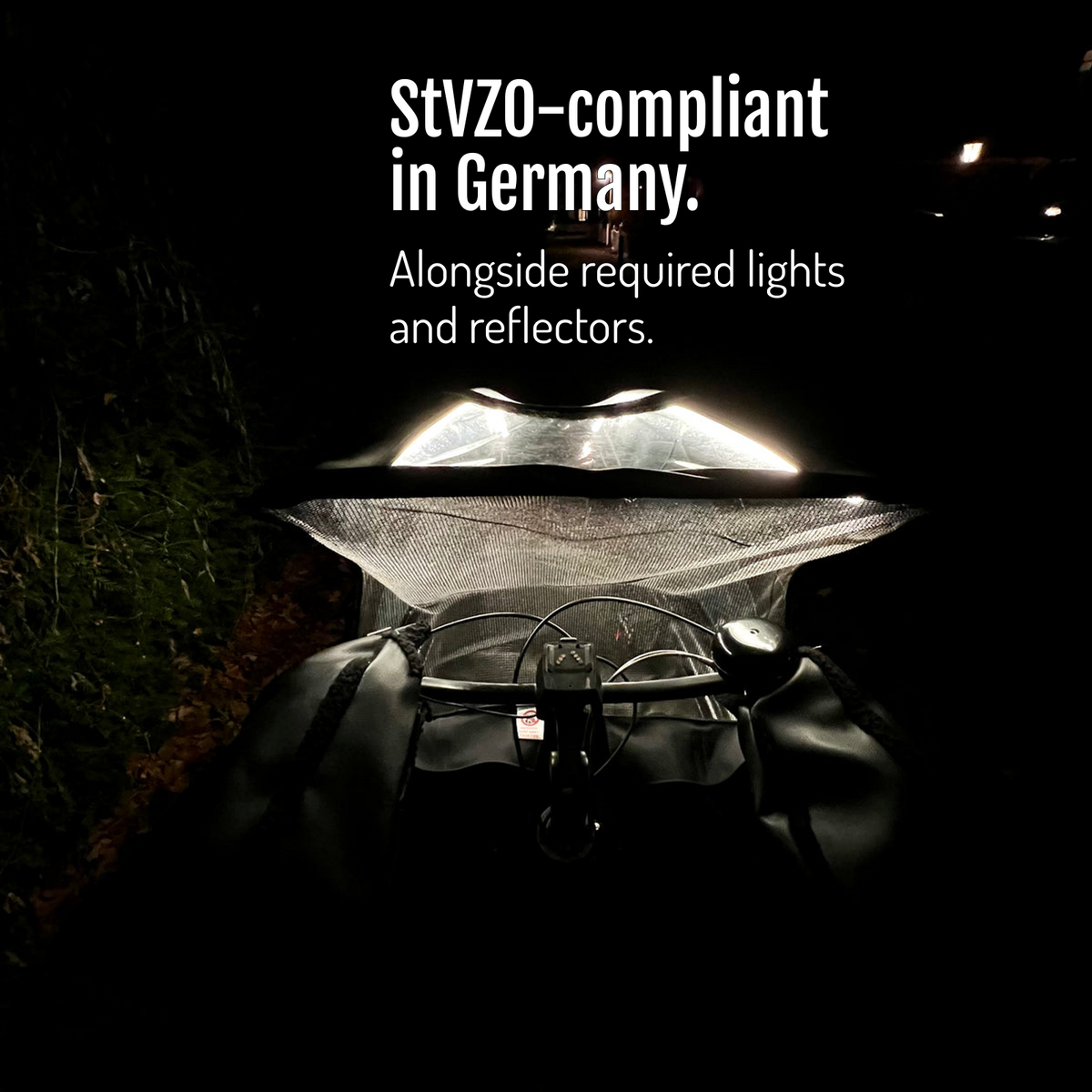 [en] View over the handlebar towards the canopy illuminated by CargoGLOW at night. StVZO-compliant in Germany, alongside required lights and reflectors.