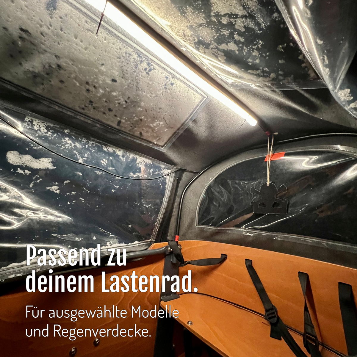 [de] CargoGLOW unter dem Regenverdeck einer Lastenradbox mit orangefarbenem Innenraum und Sitz. Passende Ausführungen für ausgewählte Modelle und Regenverdecke.